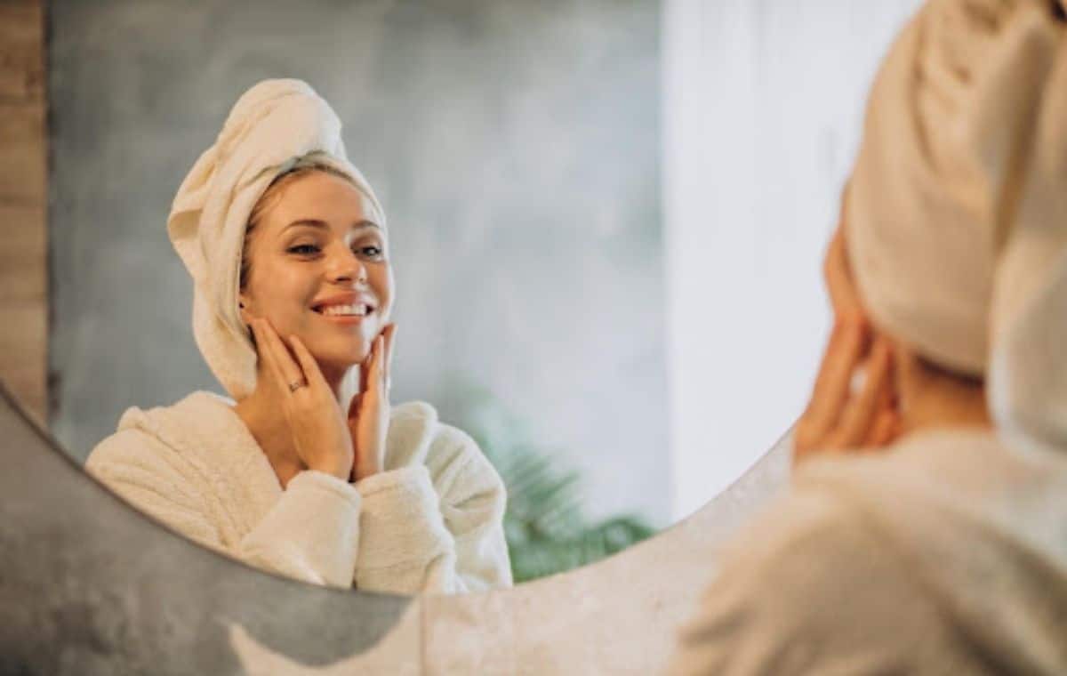 Happy woman looking at herself in the mirror and touching her face