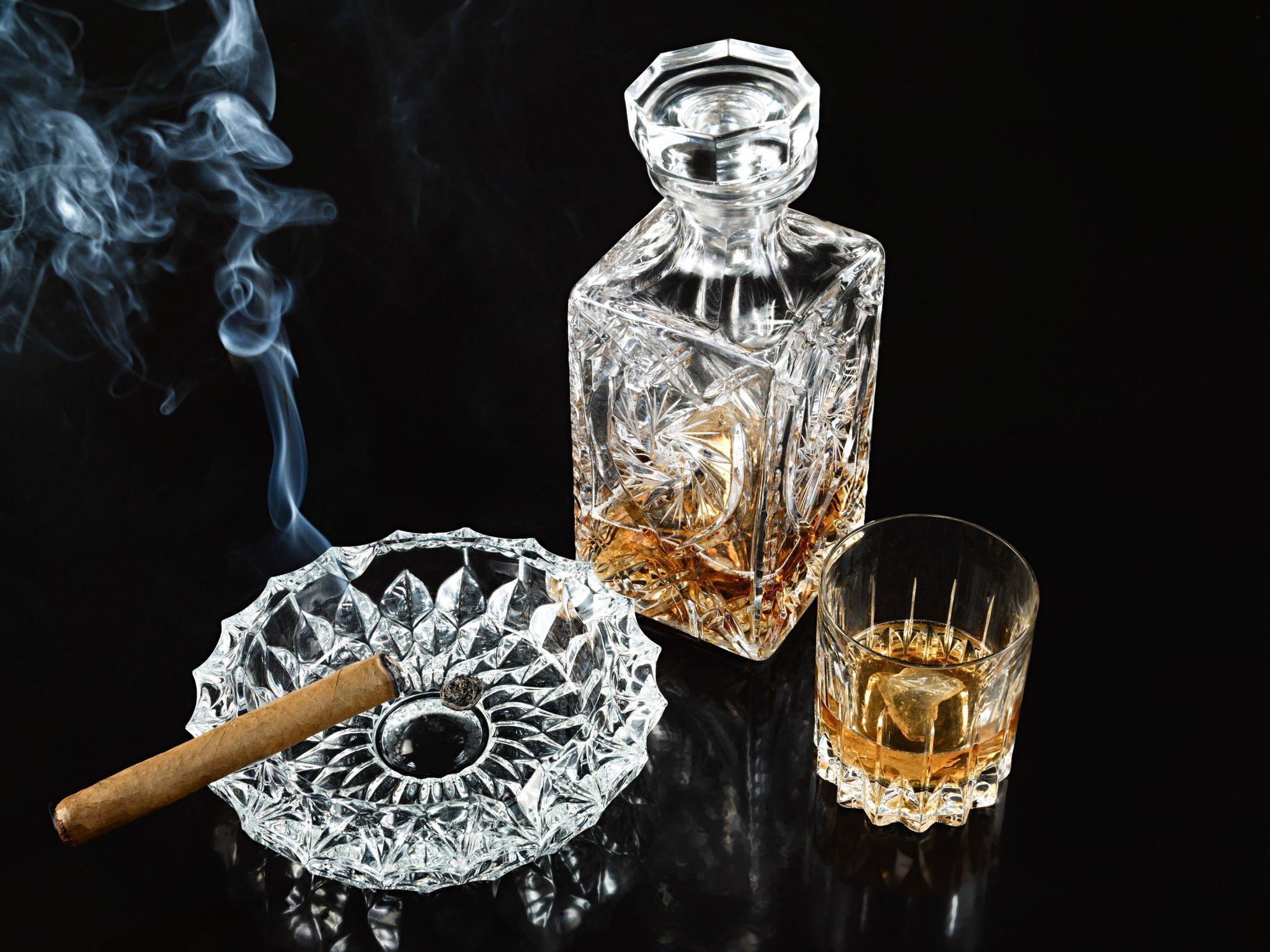 Cigar in ashtray with decanter and tumbler of whiskey
