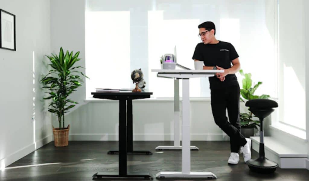 A man stands at a desk and works on a laptop.