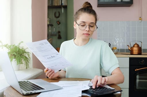 A woman sitting at a computer reviewing bills and personal loan debt obligations.