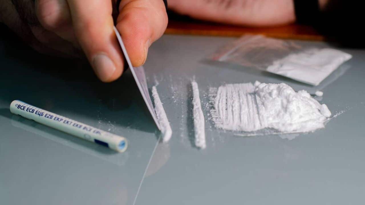 Man splits cocaine into strips and then snorts. Narcotics concept.