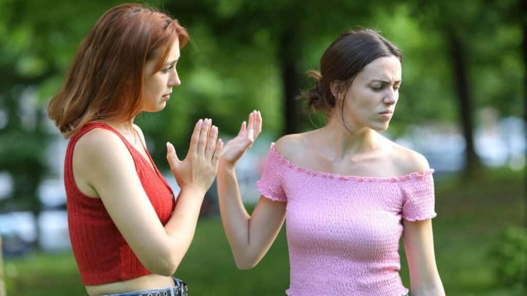 Regretful woman asking forgiveness to her friend in a park