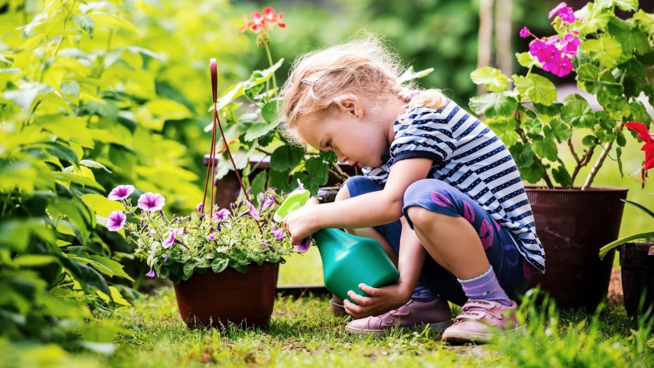 Cute little girl watering plants in the garden