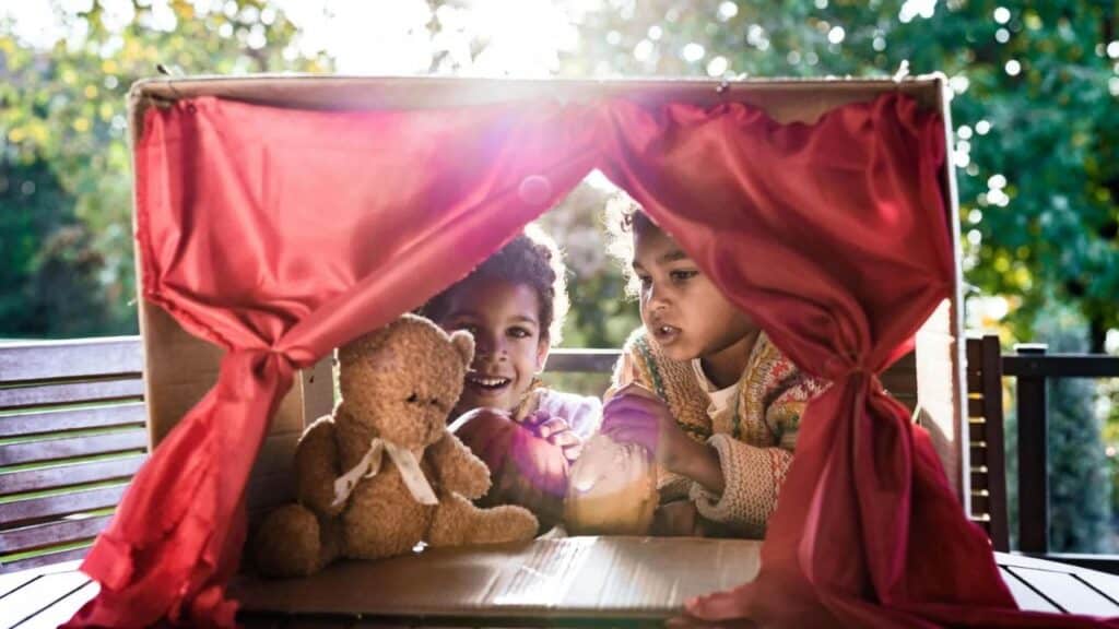 Happy black kids having a puppet show on a terrace