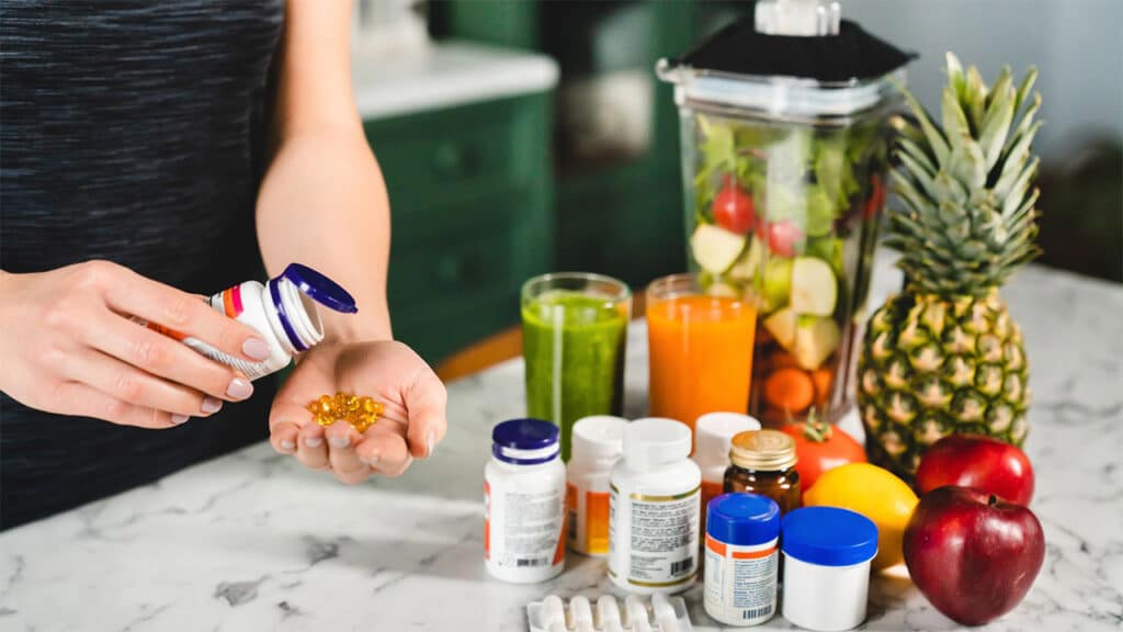  Vitamins and supplements, featuring someone pouring capsules from a bottle with fruits, juices