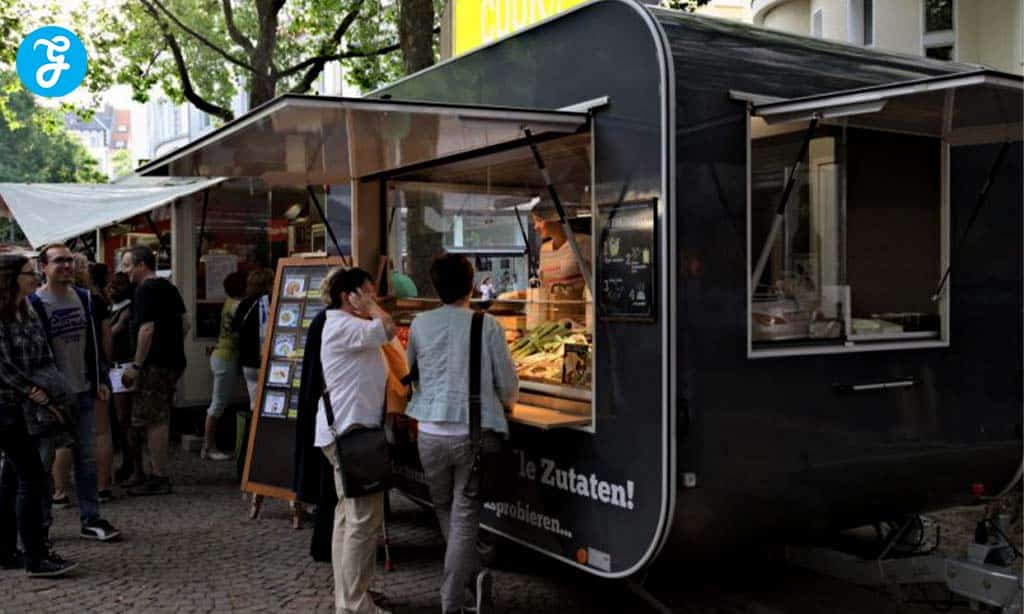 Customers ordering at a modern food truck in a bustling outdoor market