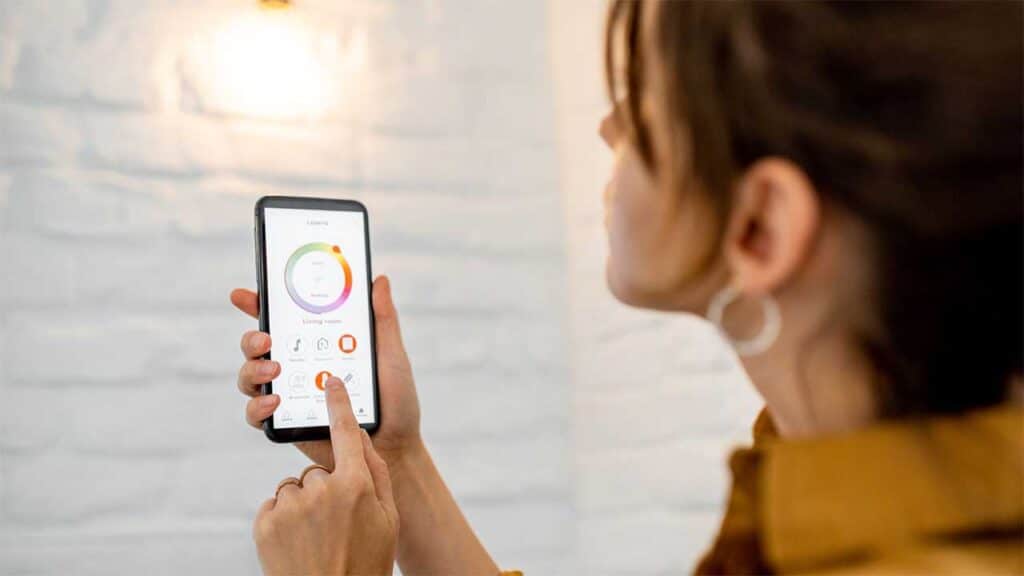 A woman using a smartphone to adjust smart home settings