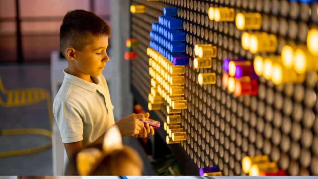 Boy playing with a giant light-up pegboard